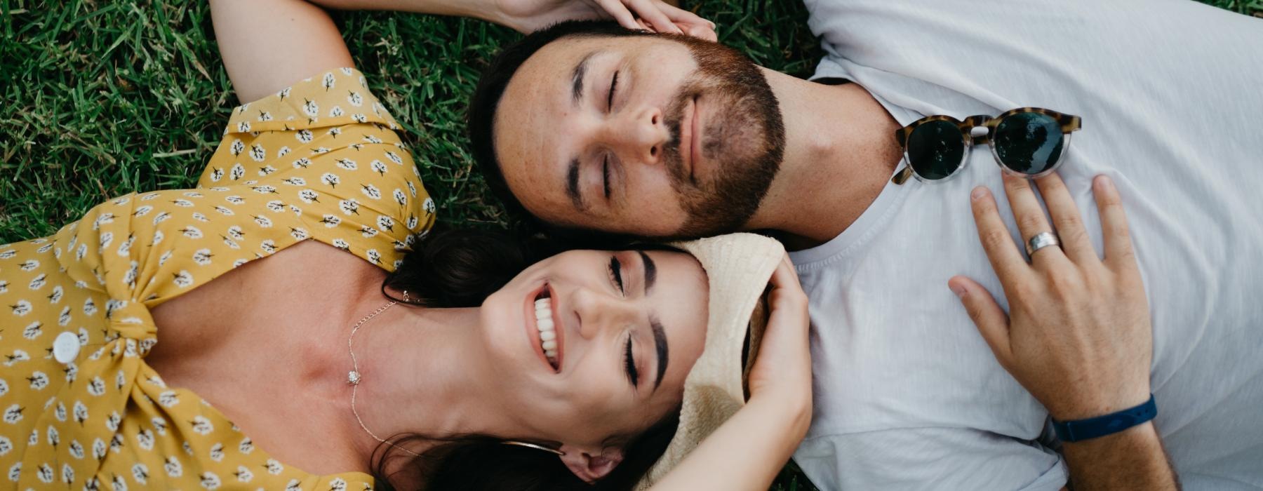 a man and woman lying in the grass